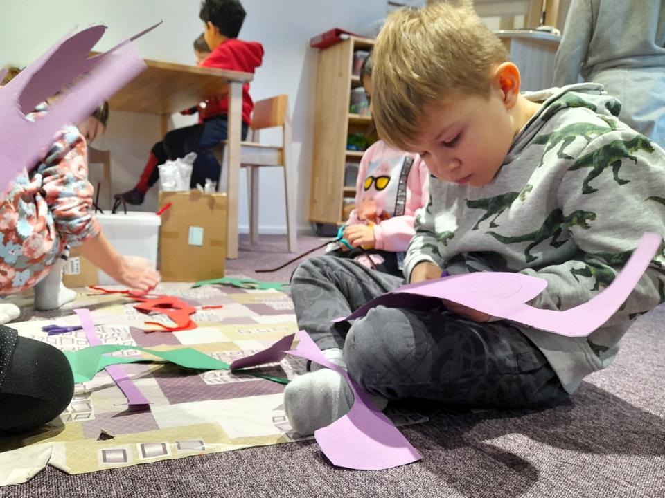 Eskarilaiset askartelevat lattialla lapsilaseja kartongista.