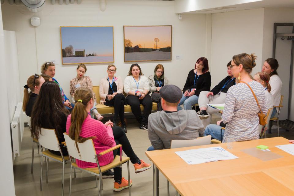 Ihmisiä istuu huoneessa ringissä Vaikuttajapäivänä.