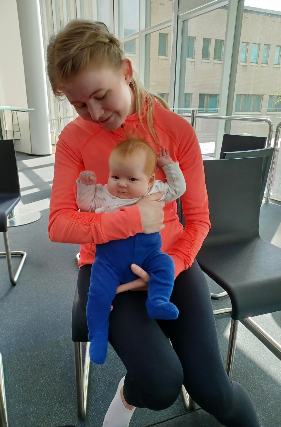 Äiti istuu tuolilla vauva sylissään ja katsoo vauvaa.